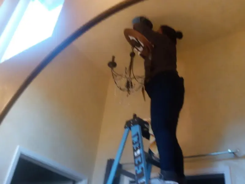 Electrician installing a chandelier in a Prosser residence